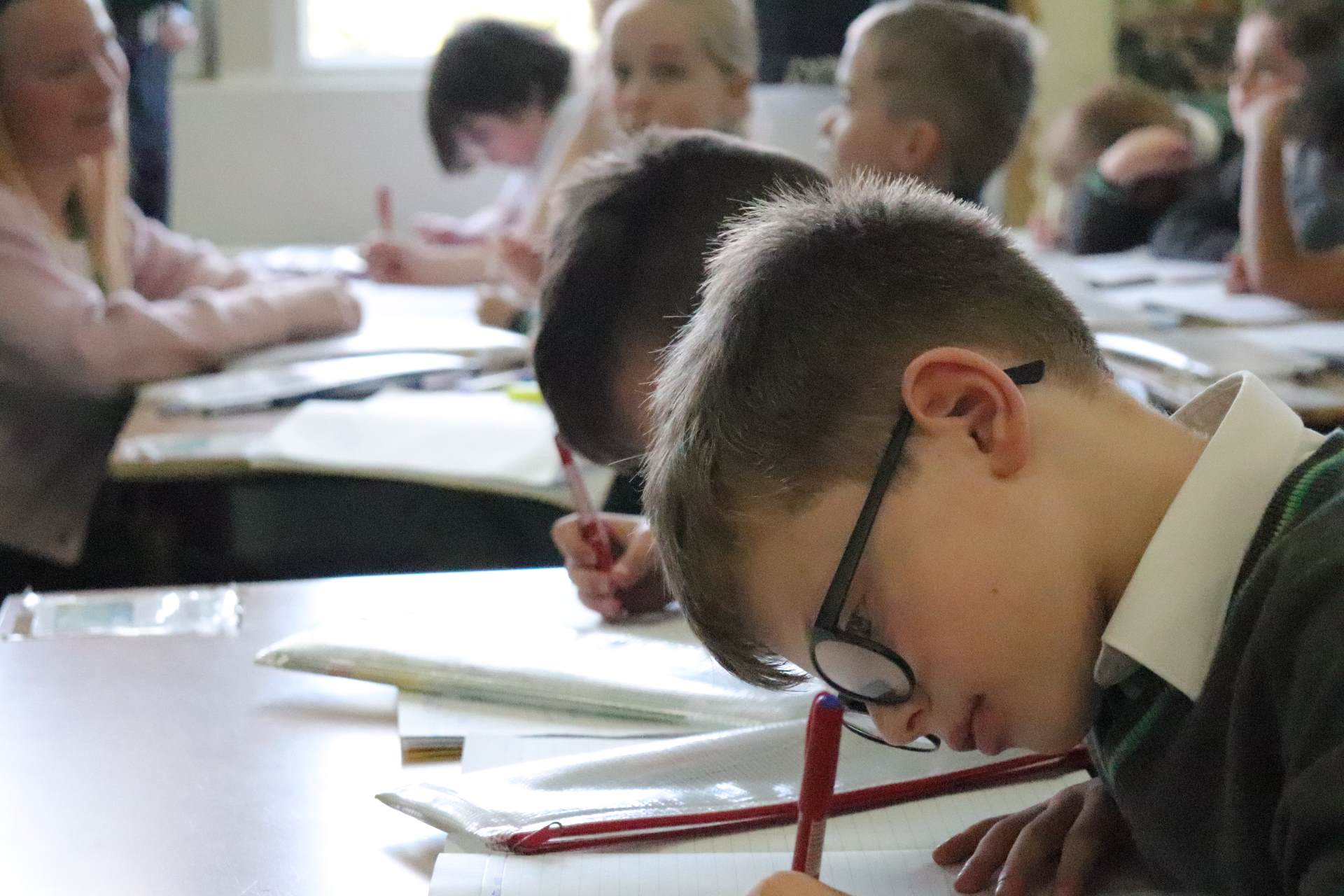 School boy writing in a classroom